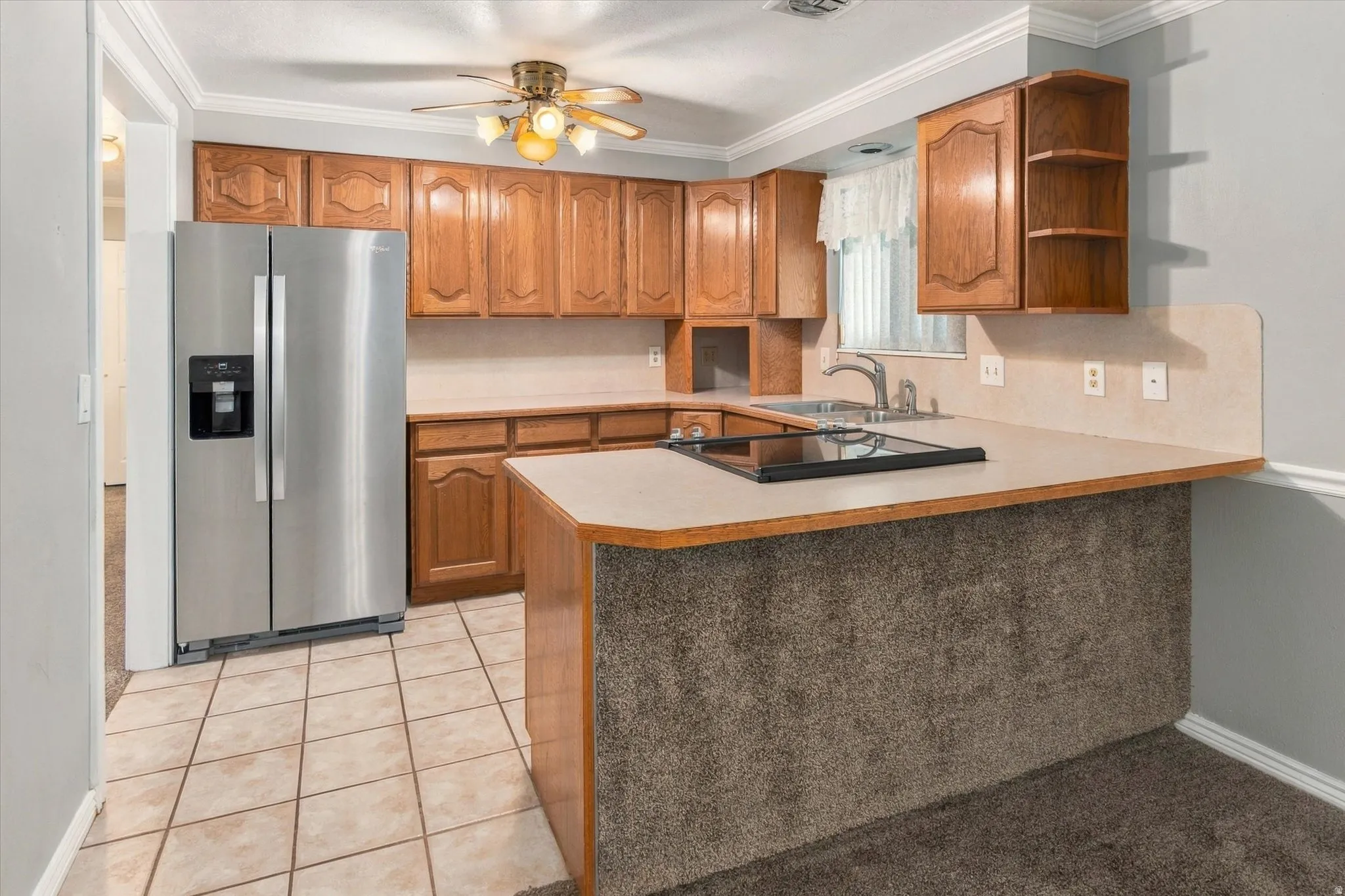 Kitchen featuring wood cabinetry, stainless steel refrigerator, tile flooring, and ceiling fan