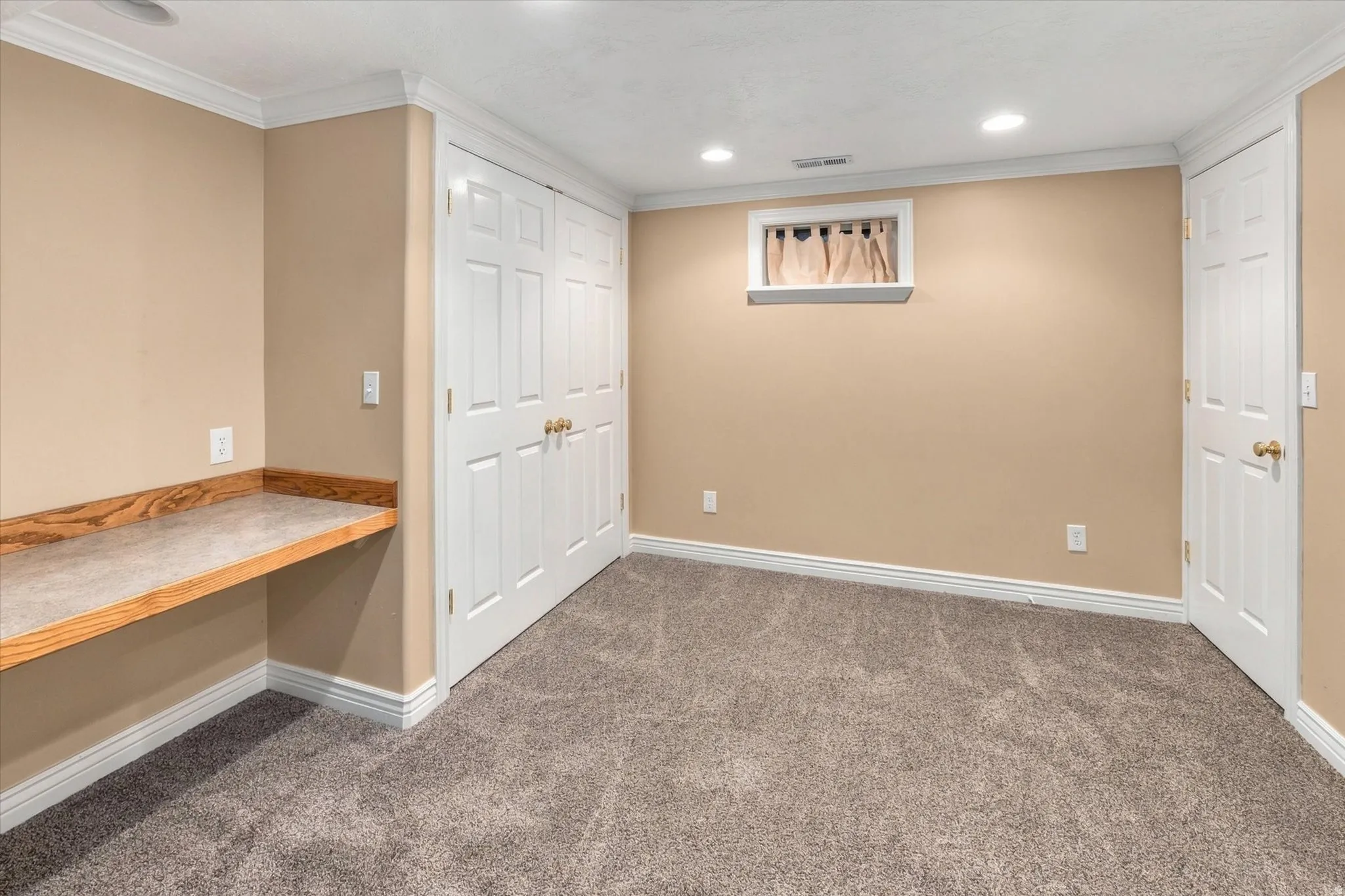 Built-in desk surface with wood-finish trim, dual paneled closet doors, recessed lighting, and crown molding