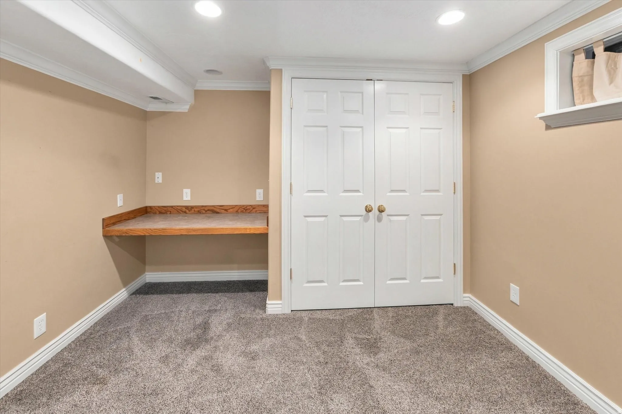Built-in desk surface with wood-finish, recessed lighting, double panel doors, and gray carpeting