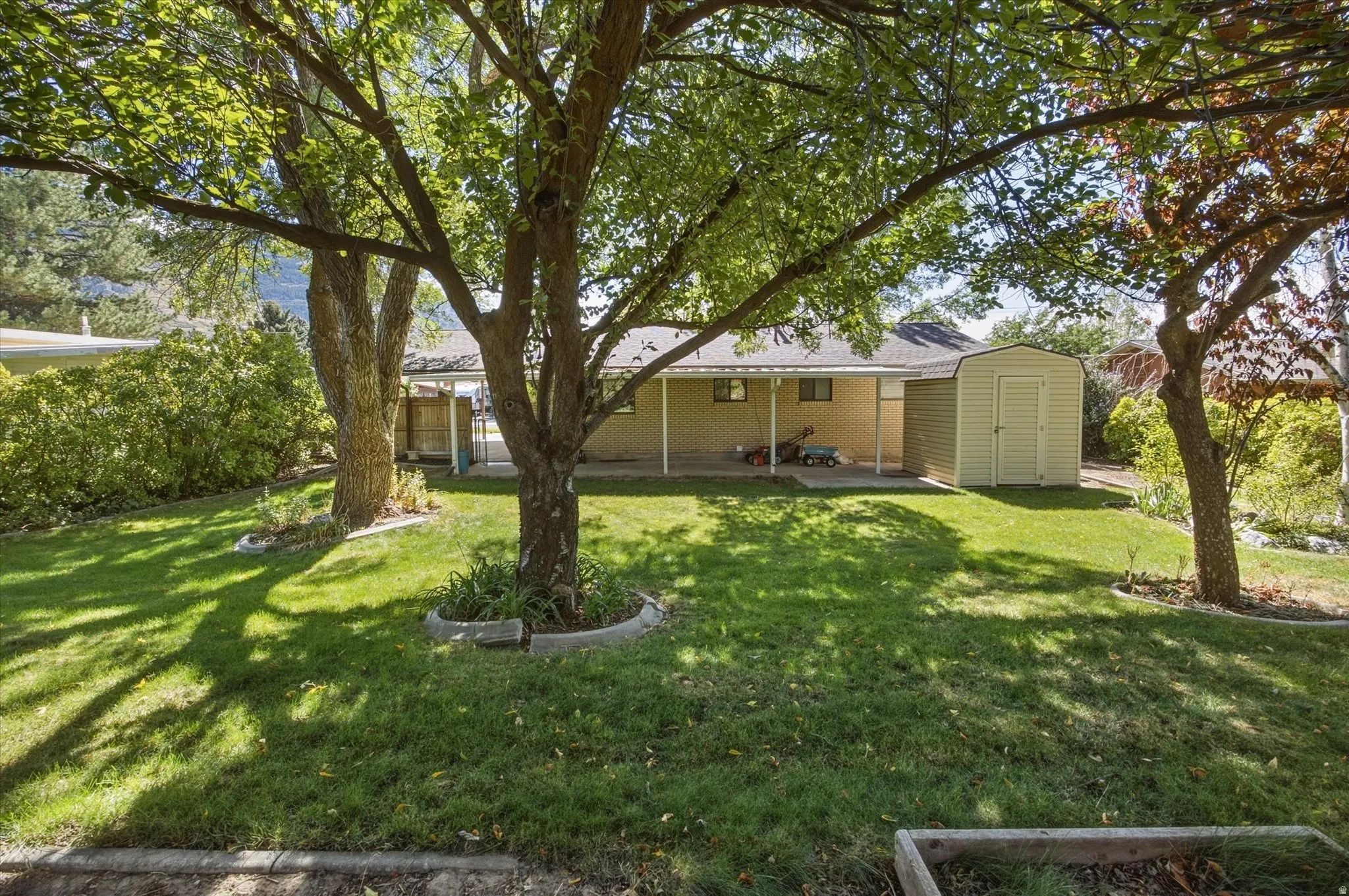 Expansive green lawn with mature trees and a rear covered patio