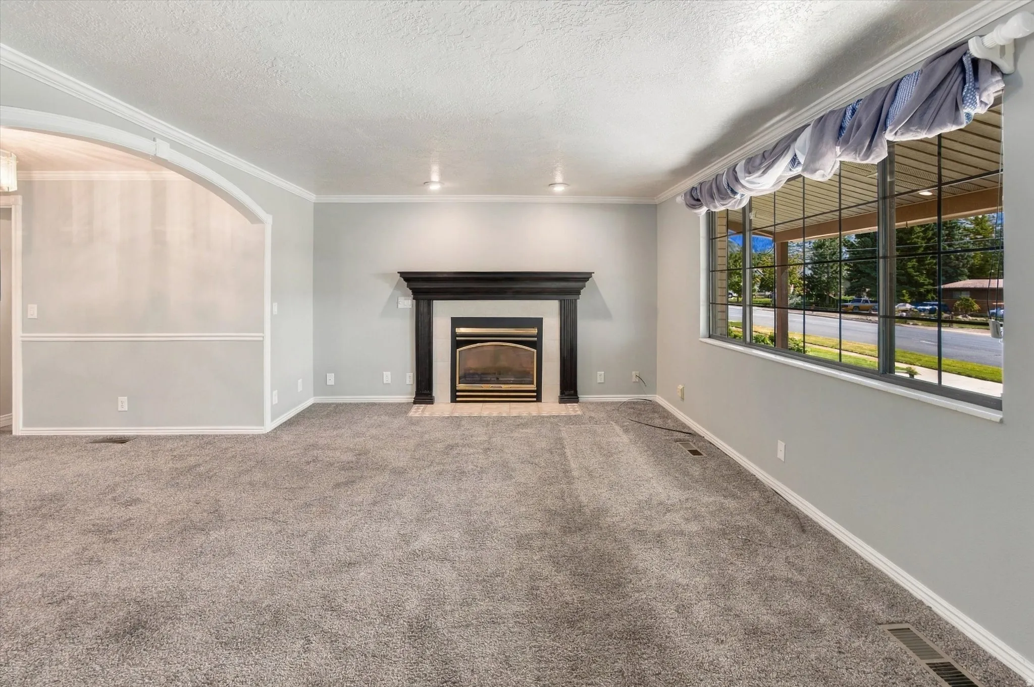Living area featuring a black mantel fireplace with a glass front, a large multi-pane window, and a coved ceiling