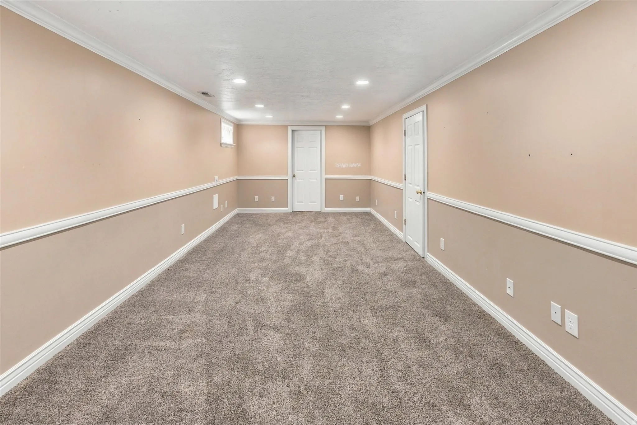 Spacious room featuring neutral carpeting, chair rail molding, and recessed lighting