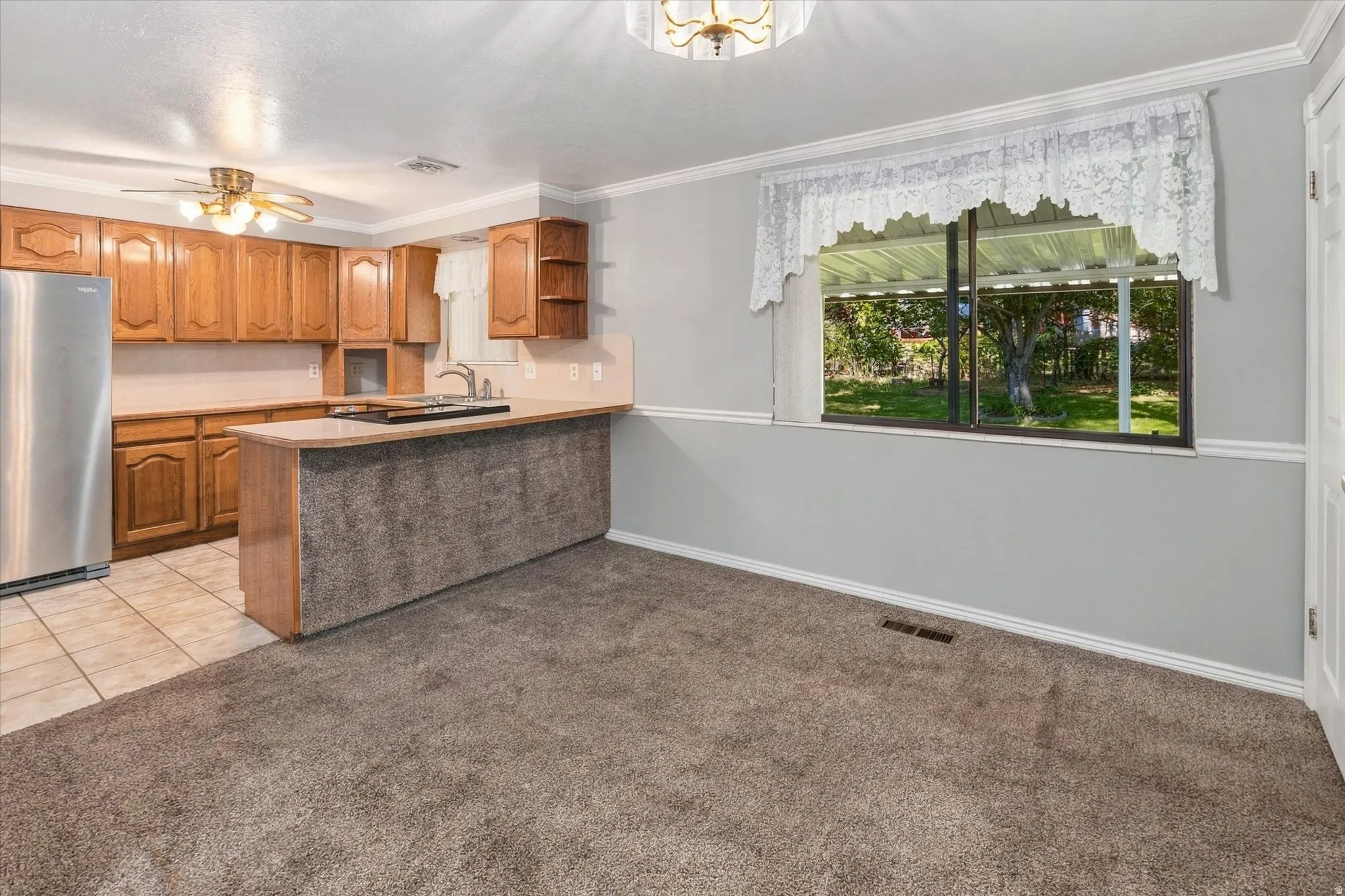 Kitchen featuring wood cabinetry, stainless steel refrigerator, and tiled flooring