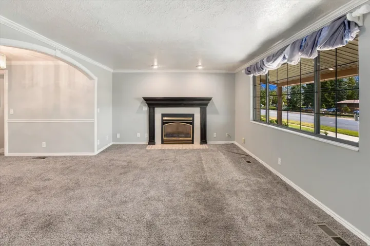 Living area featuring a black mantel fireplace with a glass front, a large multi-pane window, and a coved ceiling