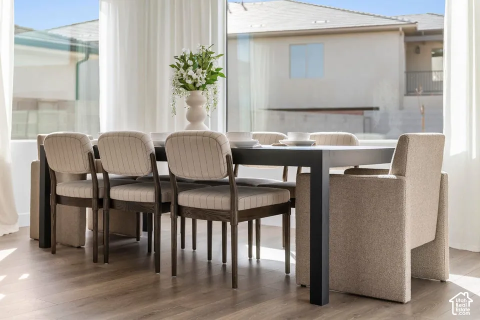 Floor-to-ceiling windows, wood-finish flooring, and white sheer drapes