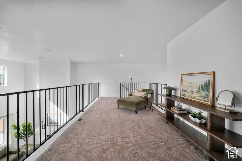 Carpeted loft area featuring a black metal railing, white shiplap accent wall, and recessed lighting