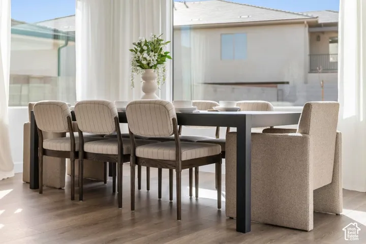 Floor-to-ceiling windows, wood-finish flooring, and white sheer drapes