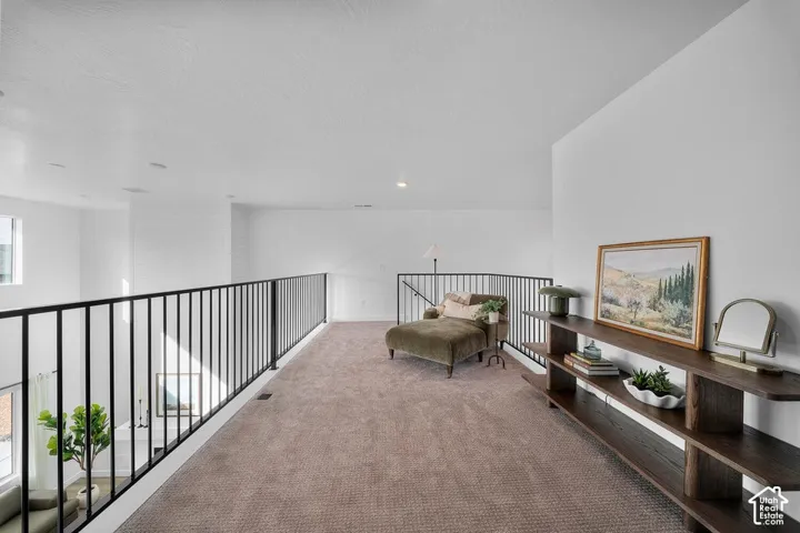 Carpeted loft area featuring a black metal railing, white shiplap accent wall, and recessed lighting