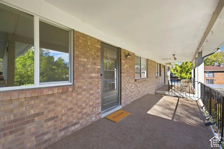 Brick exterior with multiple windows and a covered porch featuring a dark grey door