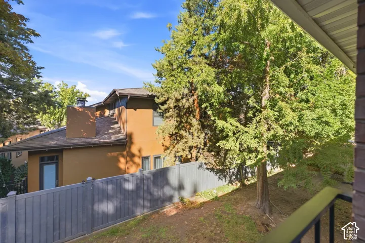 Exterior featuring an earth-toned stucco finish, dark shingle roof, and a prominent chimney