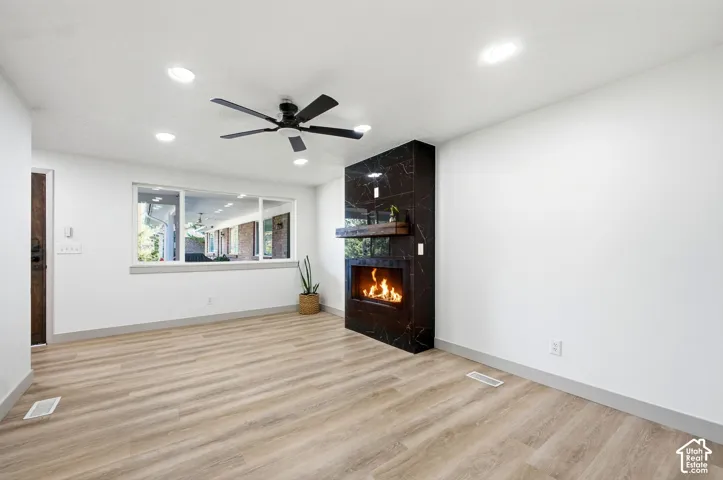 Recessed lighting, wood-finish flooring, and a contemporary fireplace with a black marble-look surround