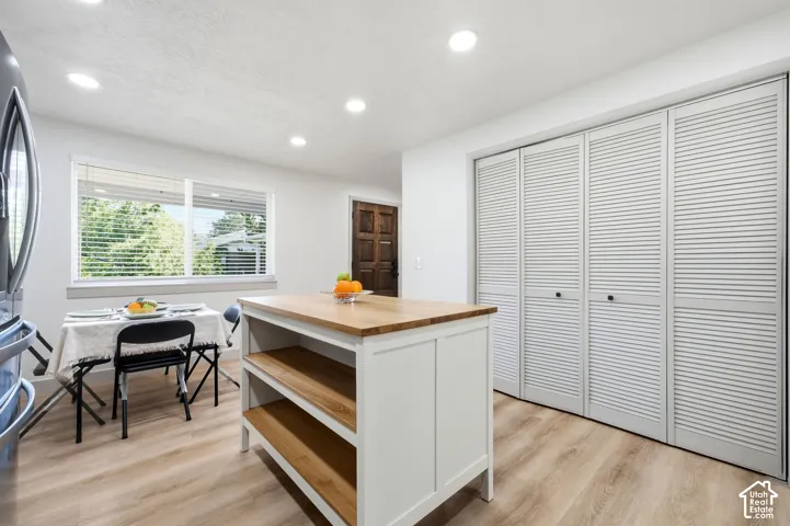 Kitchen island with wood countertop, built-in shelving, and light wood-finish flooring