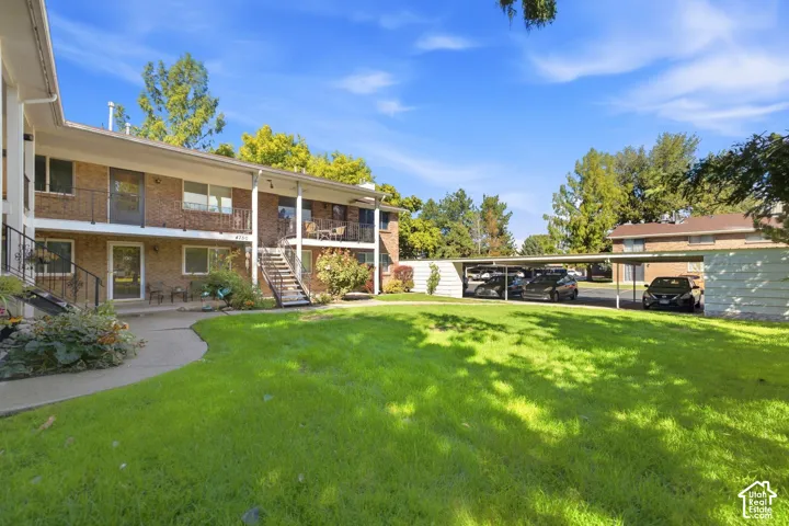 Two-story brick exterior building with covered balconies, exterior staircases, and a central lawn area
