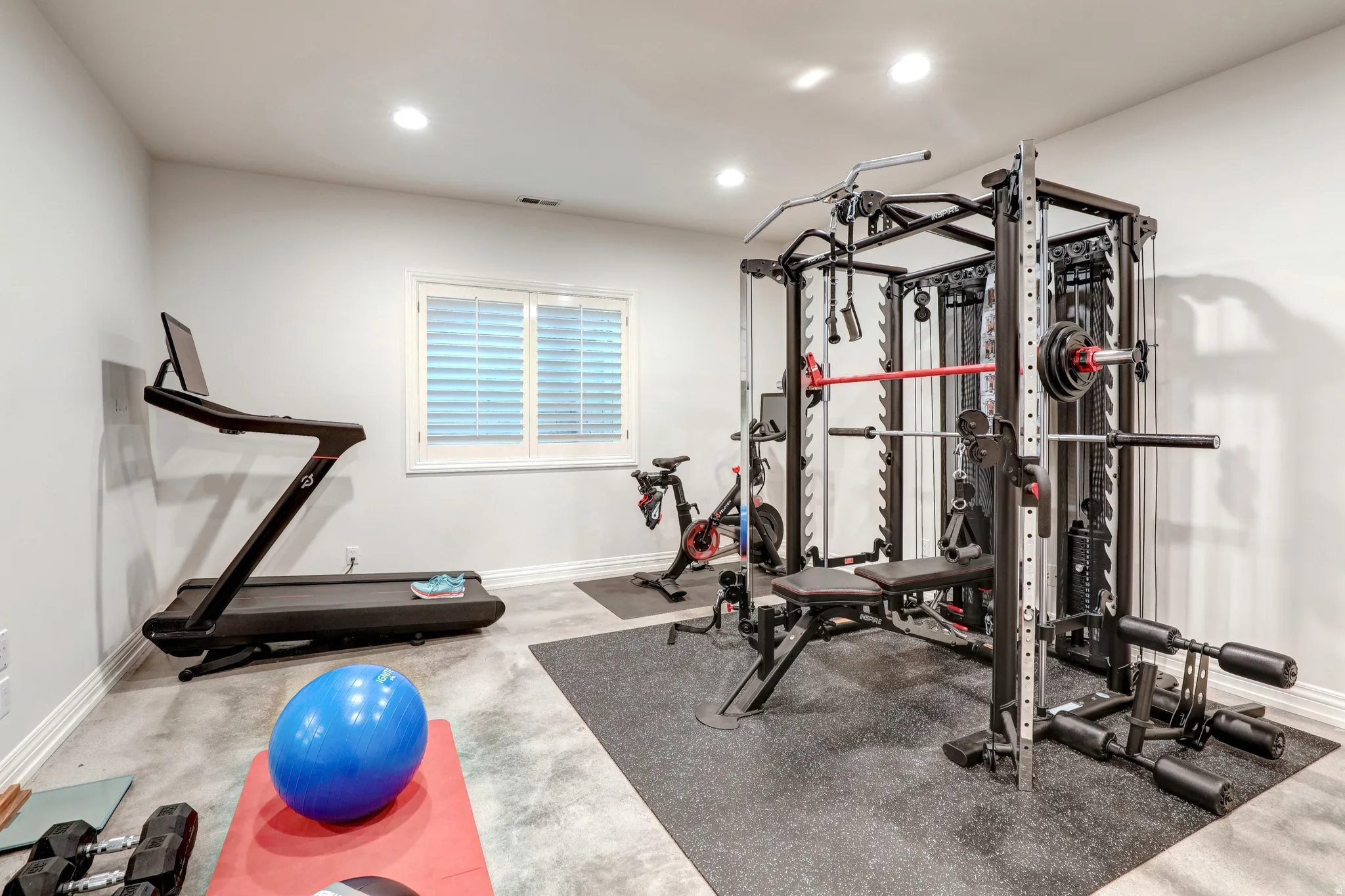 Dedicated fitness area featuring recessed lighting, a window with white louvered shutters, and light gray walls