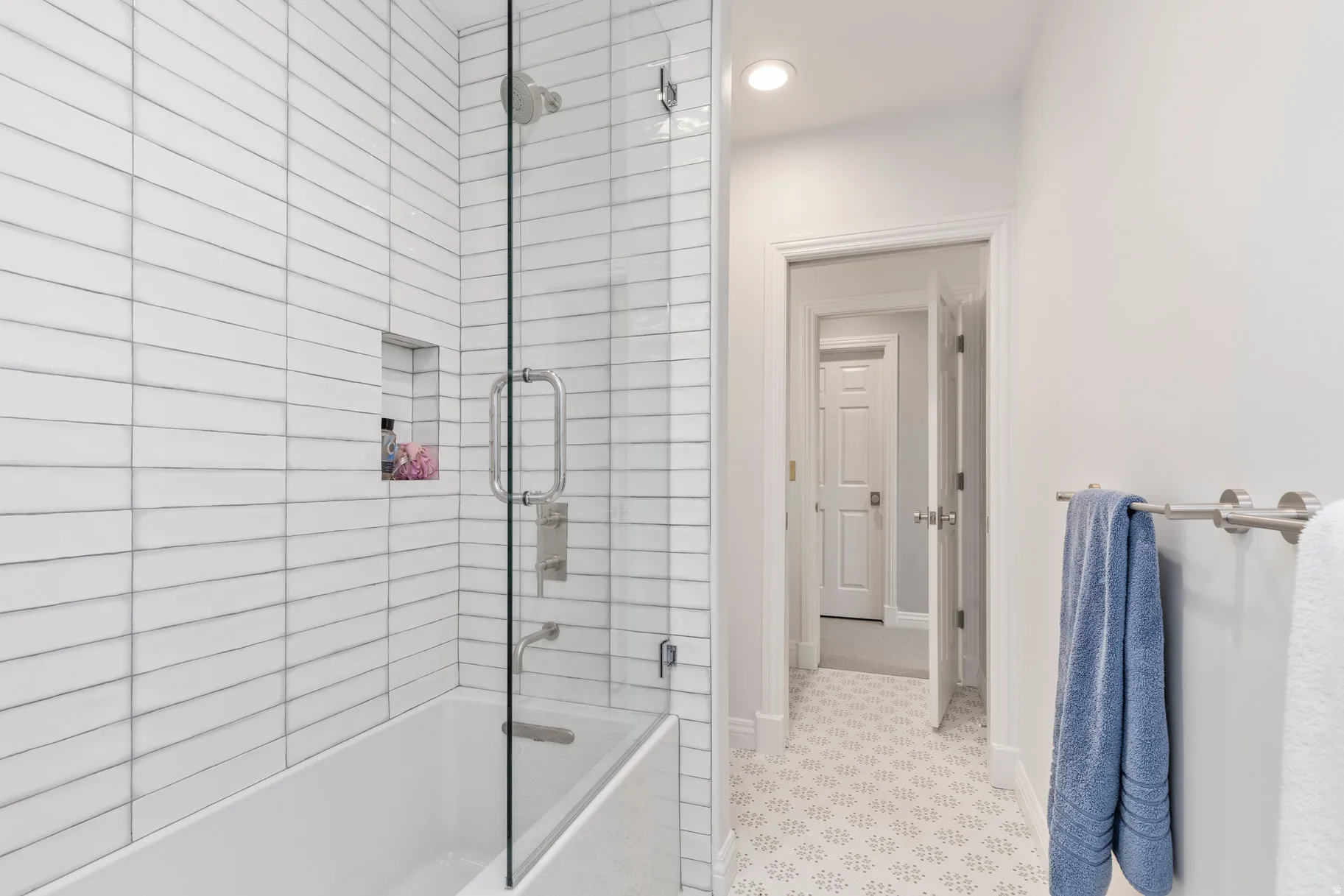 White subway tile shower with an integrated niche, glass enclosure, and a built-in tub