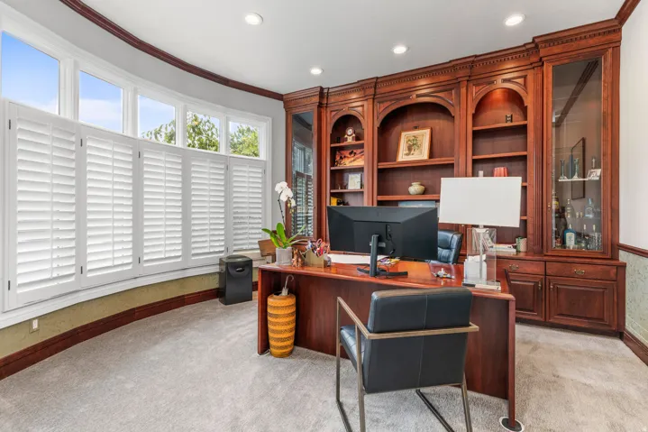 Built-in custom wood cabinetry, recessed lighting, expansive bay windows, wood-finish flooring, and wall paneling