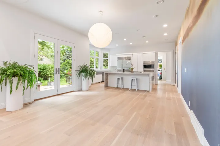 Hardwood flooring, French doors, recessed lighting, built-in kitchen cabinetry, and a kitchen island with seating