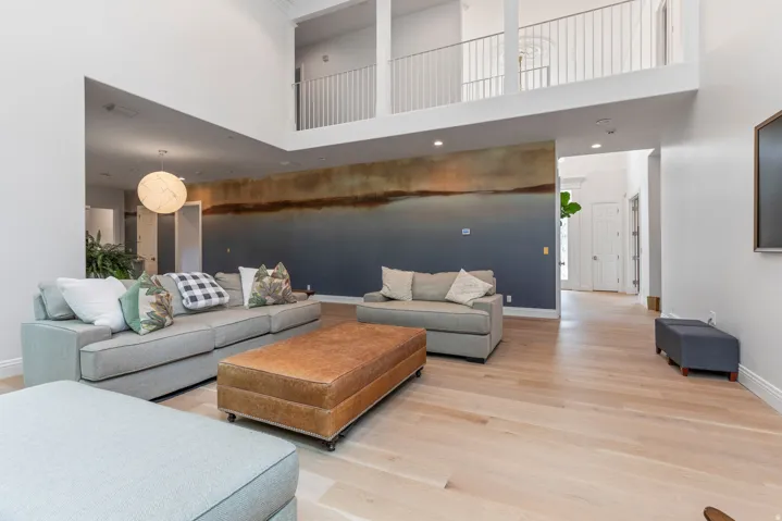 High ceilings with an open loft area featuring a white railing, light wood-finish flooring, and recessed lighting