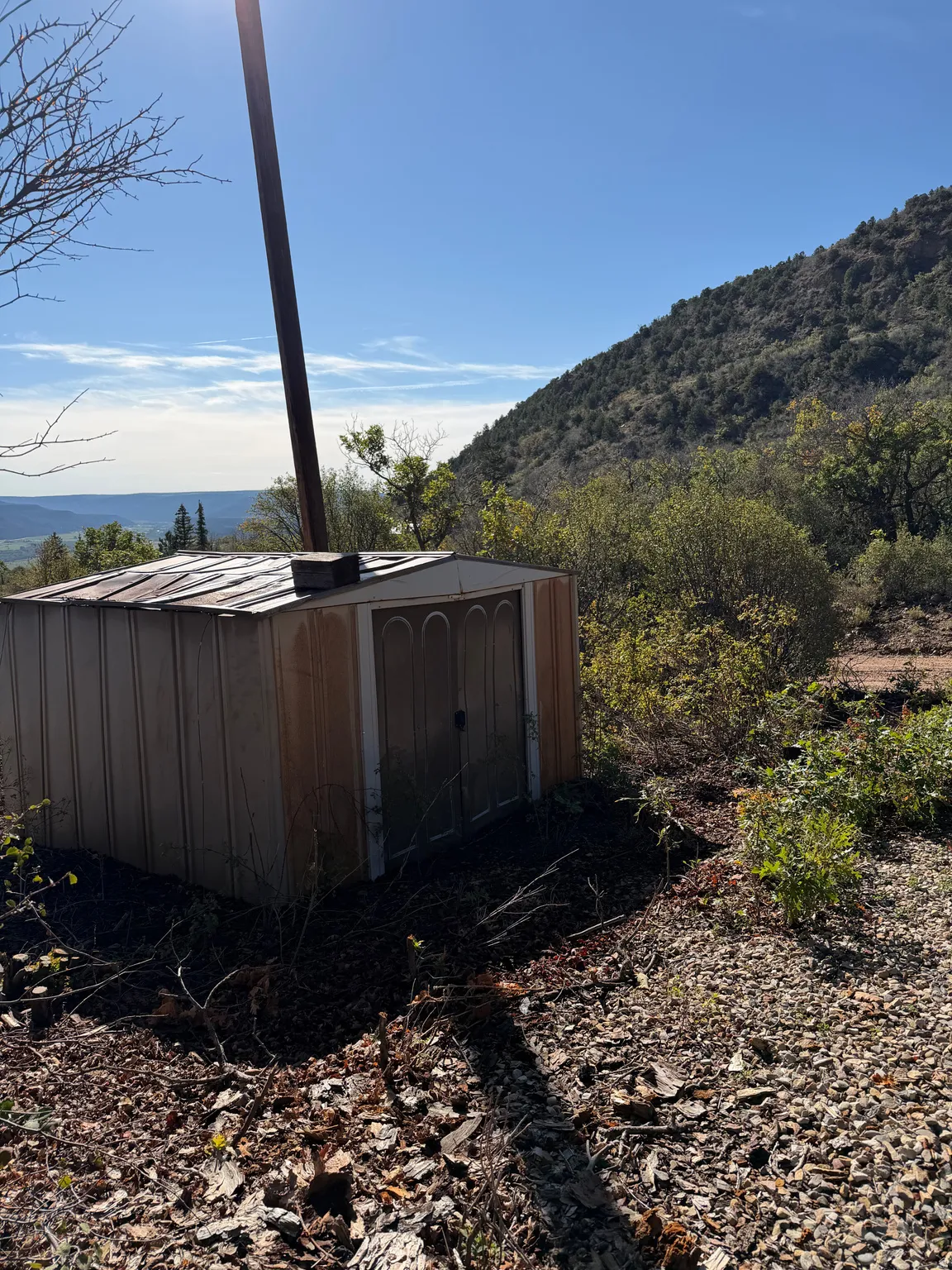 Storage shed with a corrugated metal roof and a natural landscape setting