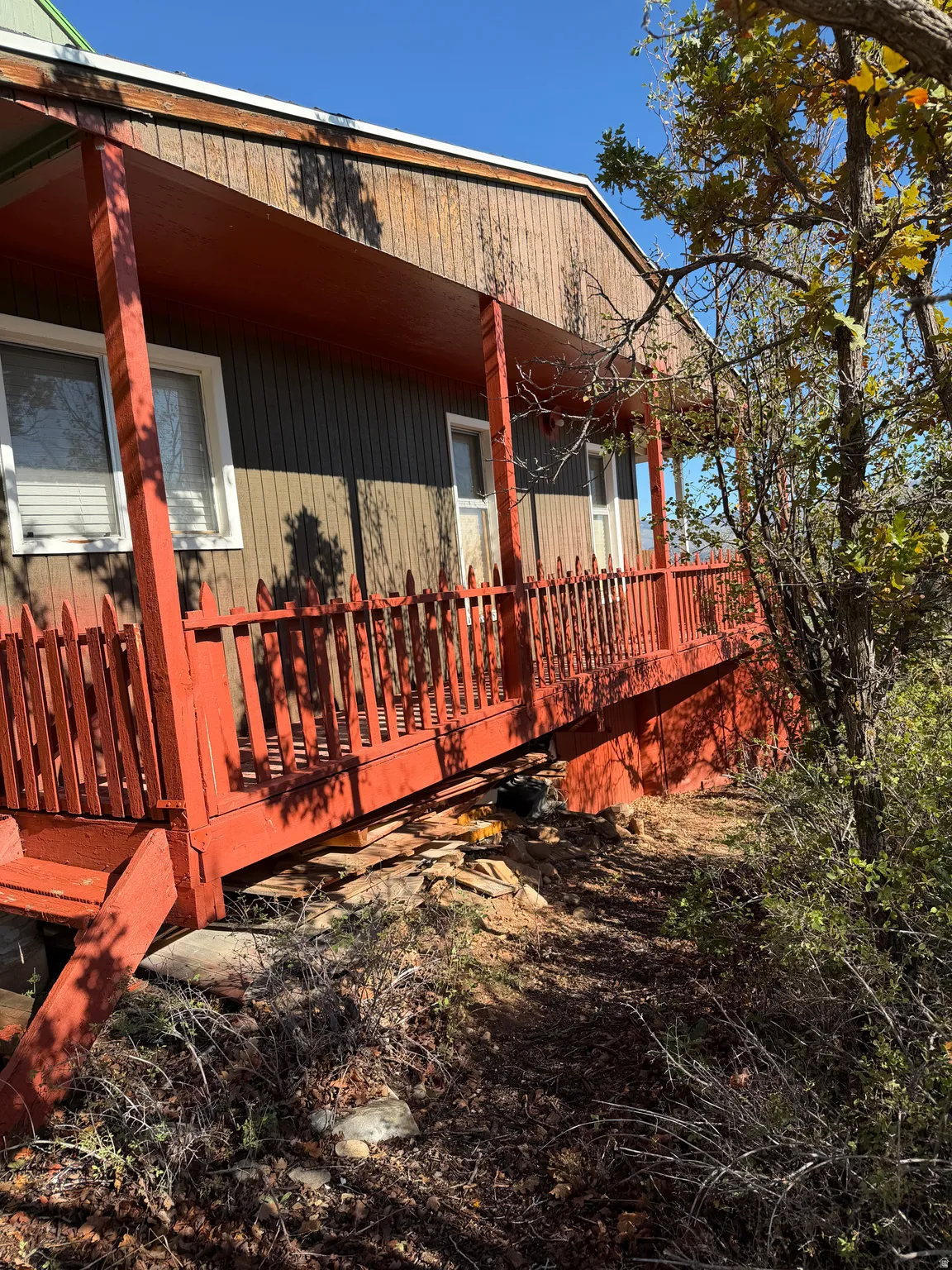 Front exterior featuring wood siding, an extended wooden porch, and an elevated foundation