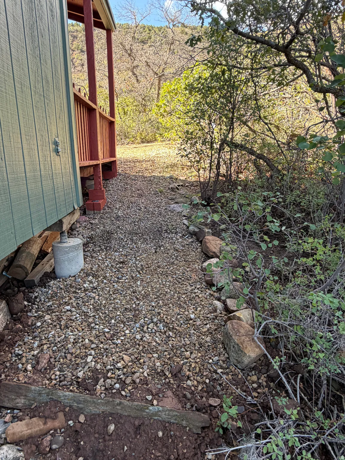 Gravel pathway alongside the building, featuring natural stone edging and surrounding vegetation