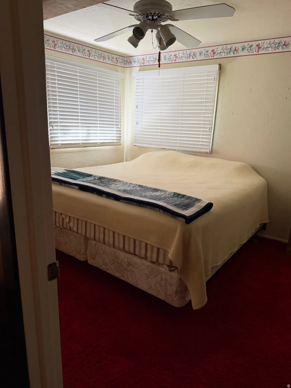 Room featuring textured walls, red carpeting, and a ceiling fan with integrated lighting