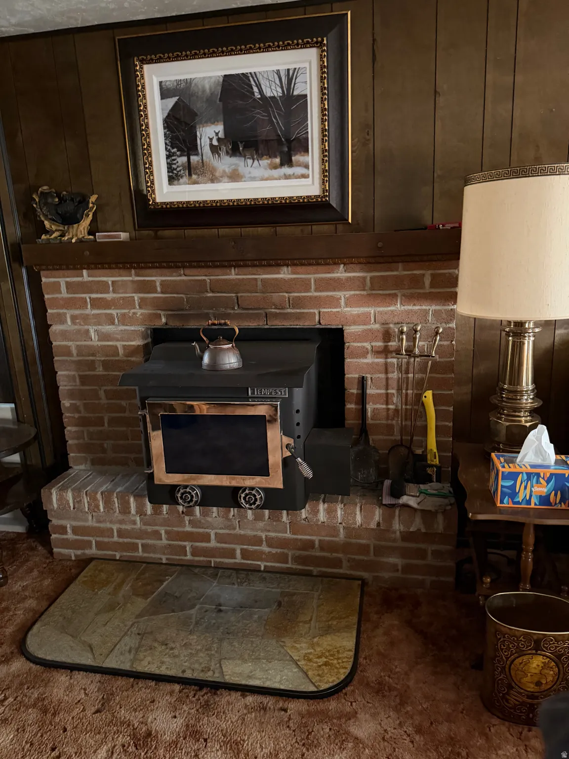 Brick fireplace with a wood-burning stove insert and a wood mantel