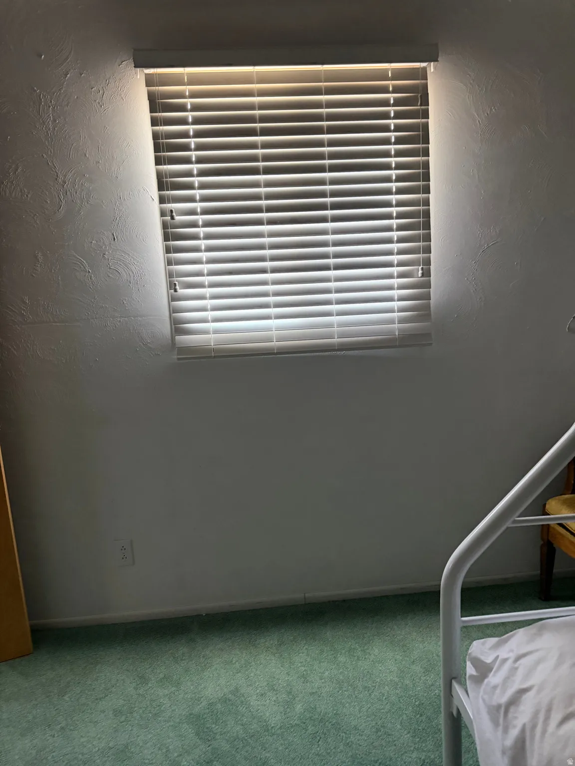 Window with horizontal blinds and textured white walls