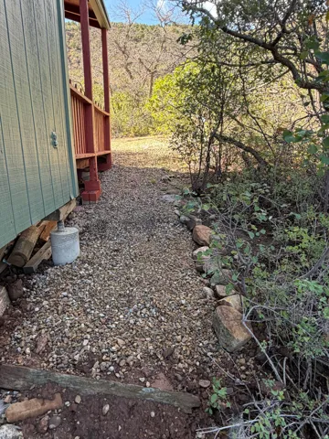 Gravel pathway alongside the building, featuring natural stone edging and surrounding vegetation