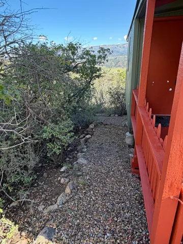 Gravel pathway with a rock border, alongside a structure with painted siding and a railing