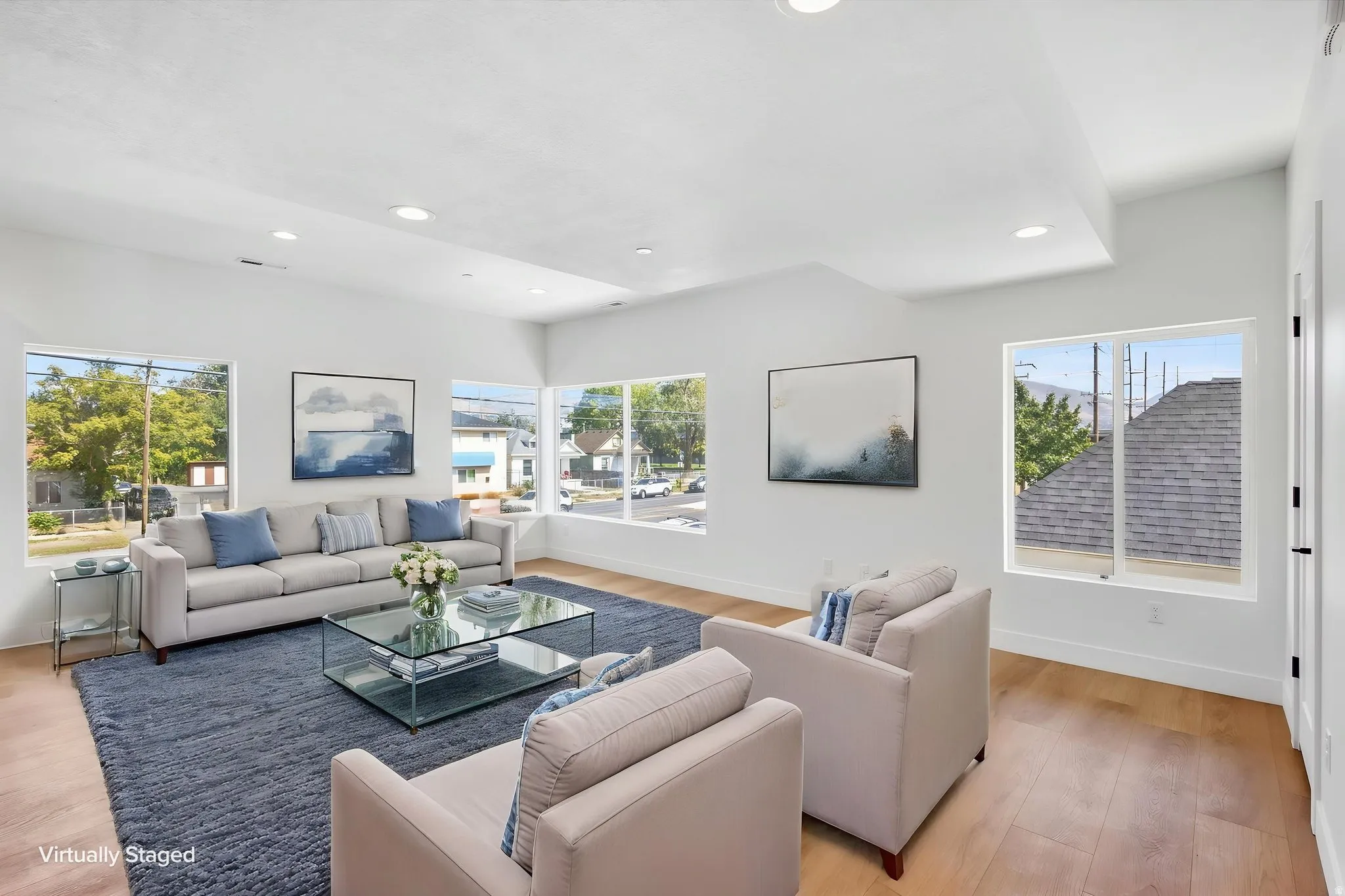 Vaulted ceilings with recessed lighting, light wood-finish flooring, white walls, and multiple large windows