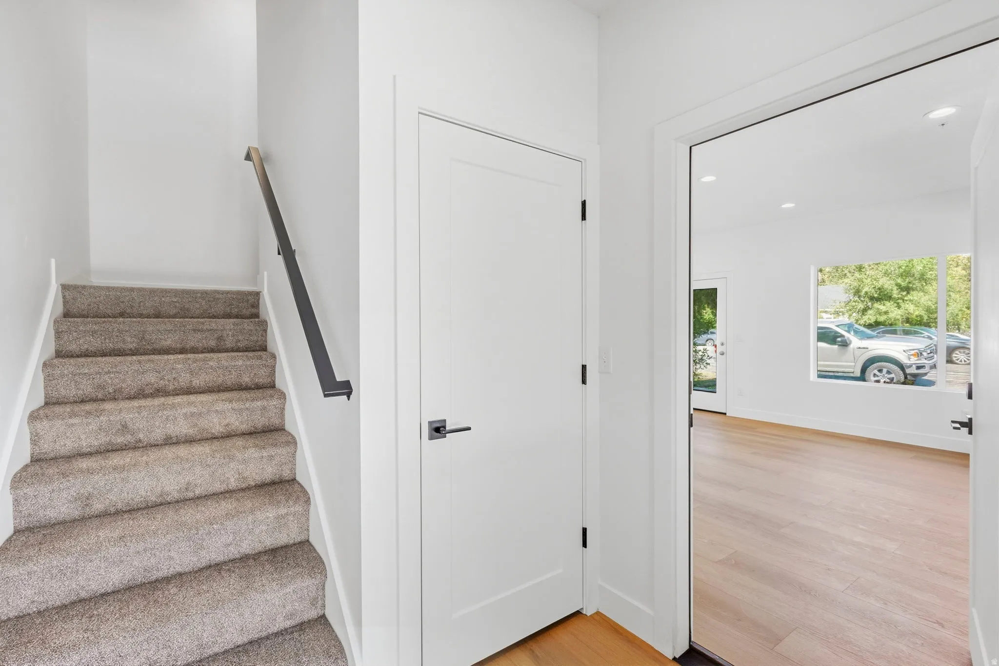 Staircase with carpeted treads and a black handrail