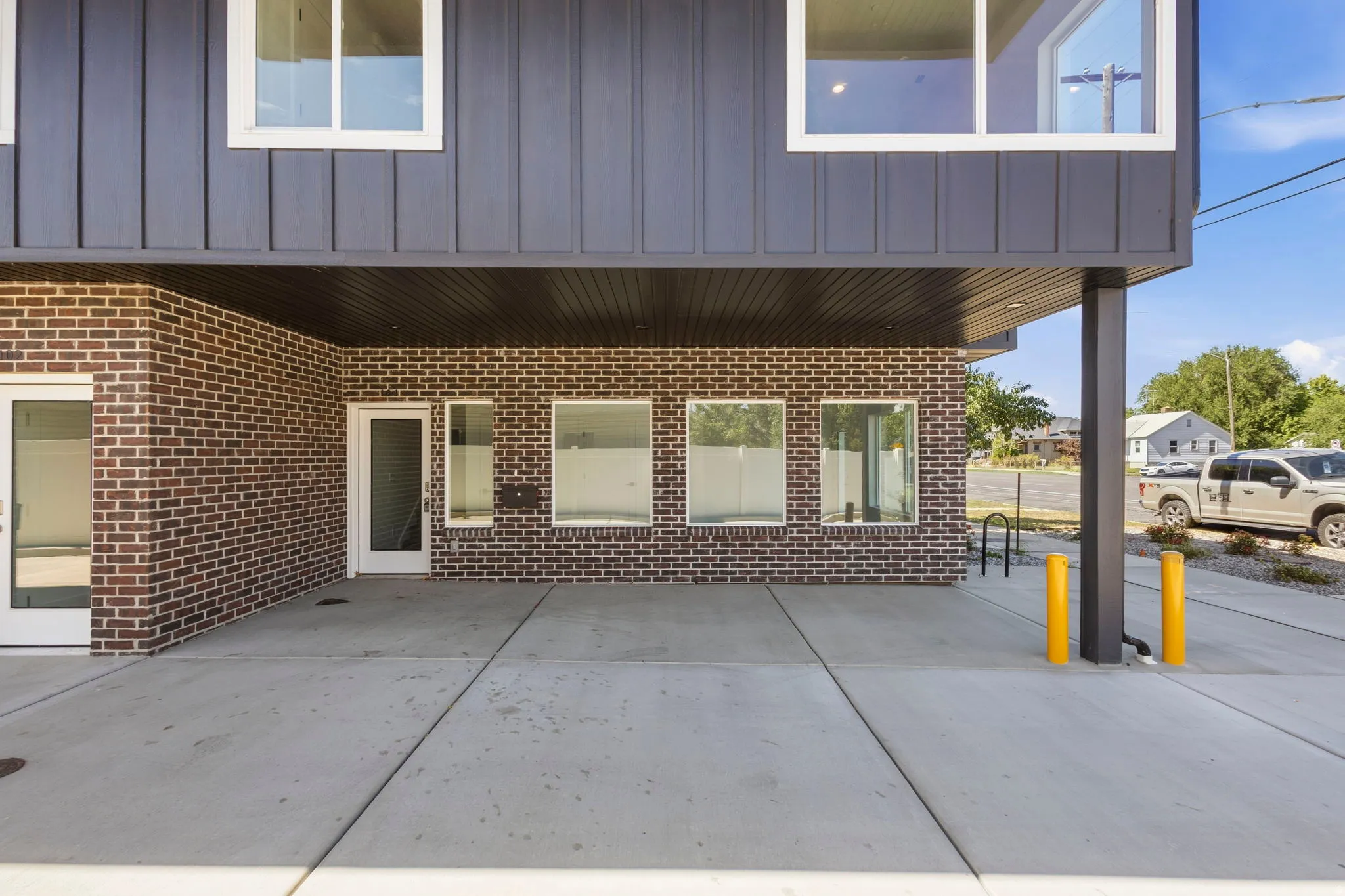 Concrete ground-level patio with dark brick and vertical panel siding