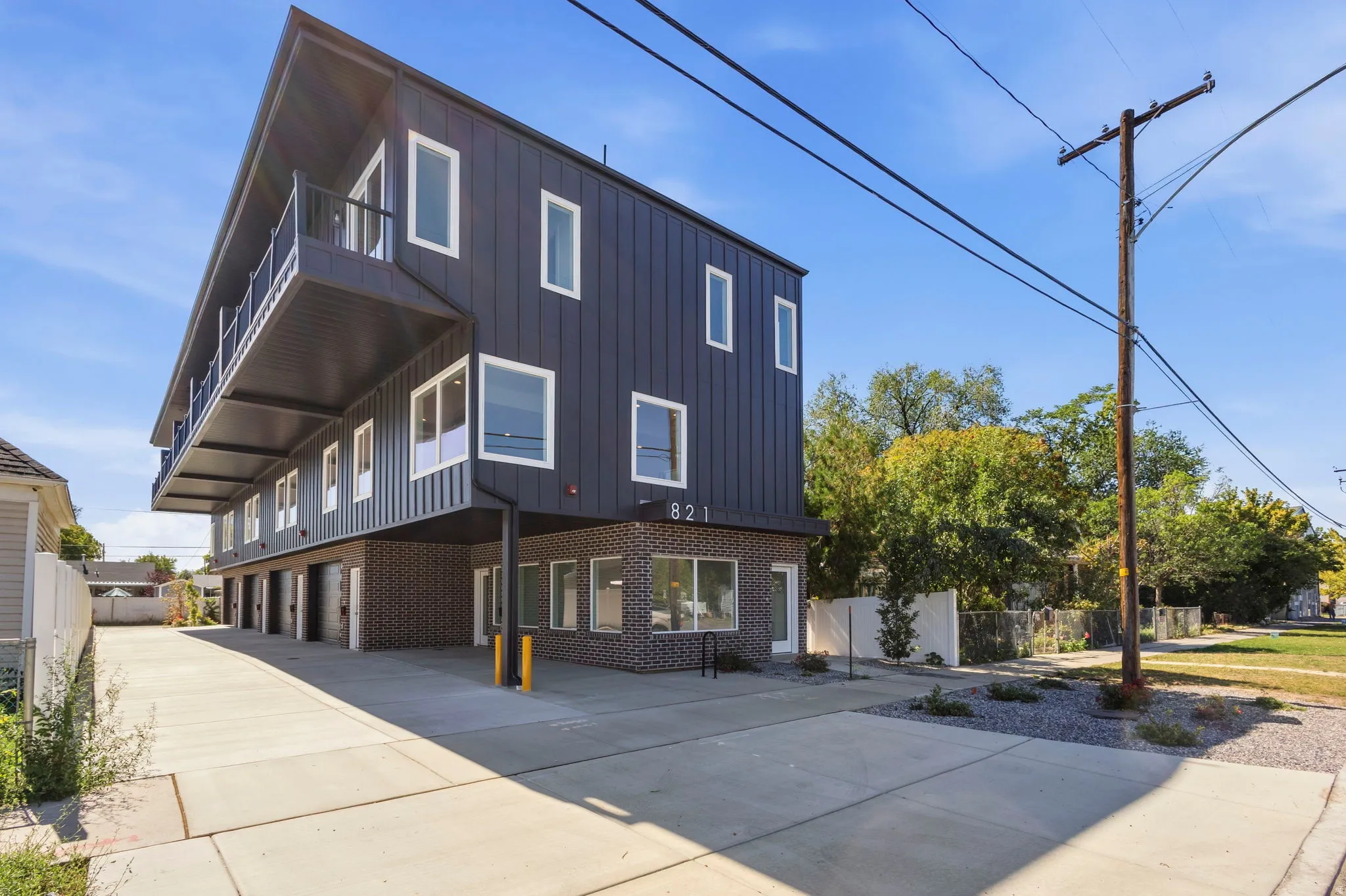 Modern multi-story building featuring vertical panel siding, brick accents, and a distinctive sloped roofline
