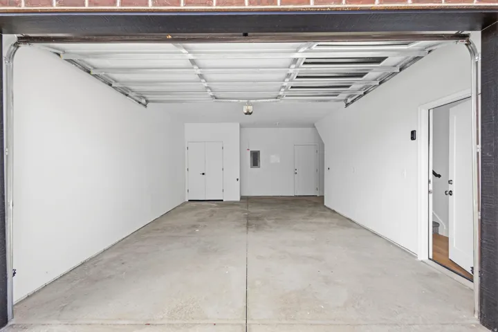 Spacious garage with a concrete floor, bright white walls, and an overhead light fixture