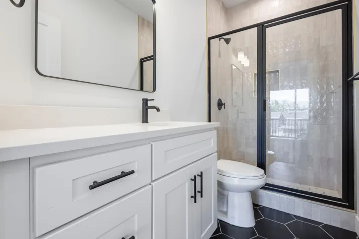 White vanity with matte black hardware, integrated sink, and wall-mounted faucet