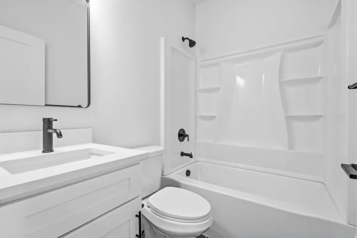 White vanity with a rectangular sink and matte black faucet