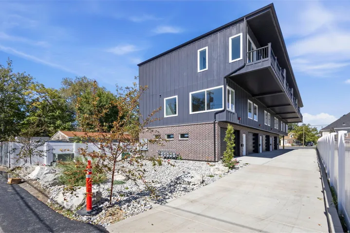 Modern building exterior featuring dark vertical siding and a brick base