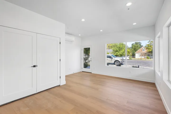 Recessed lighting, wood-finish flooring, white flat-panel doors with matte black hardware, large windows, and a glass-paneled exterior door