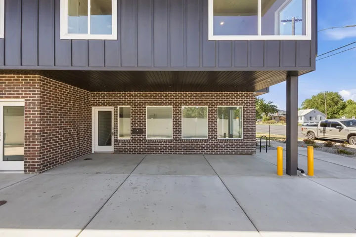 Concrete ground-level patio with dark brick and vertical panel siding