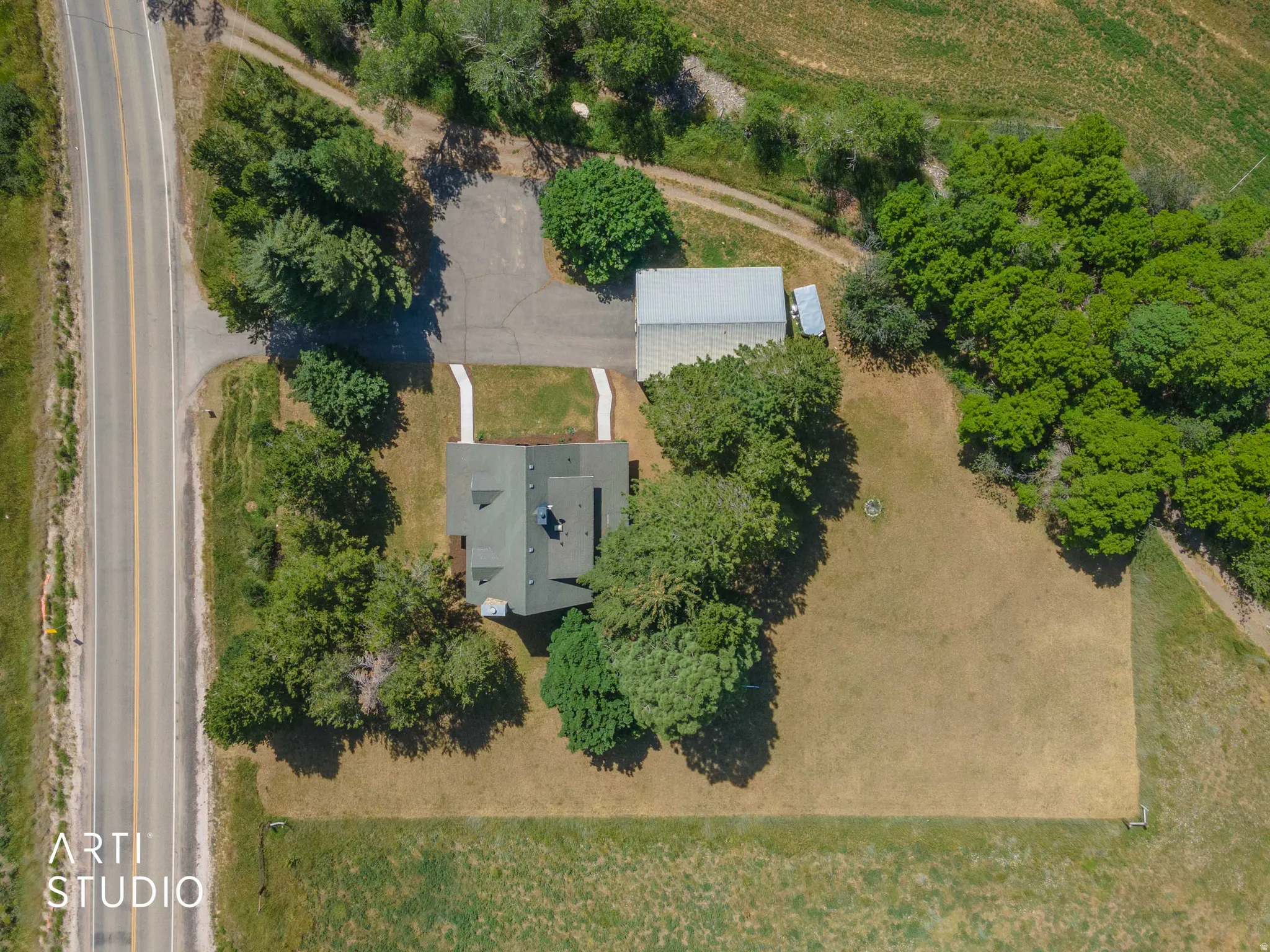 Property featuring a pitched roof, extensive tree coverage, an asphalt driveway, and a detached outbuilding