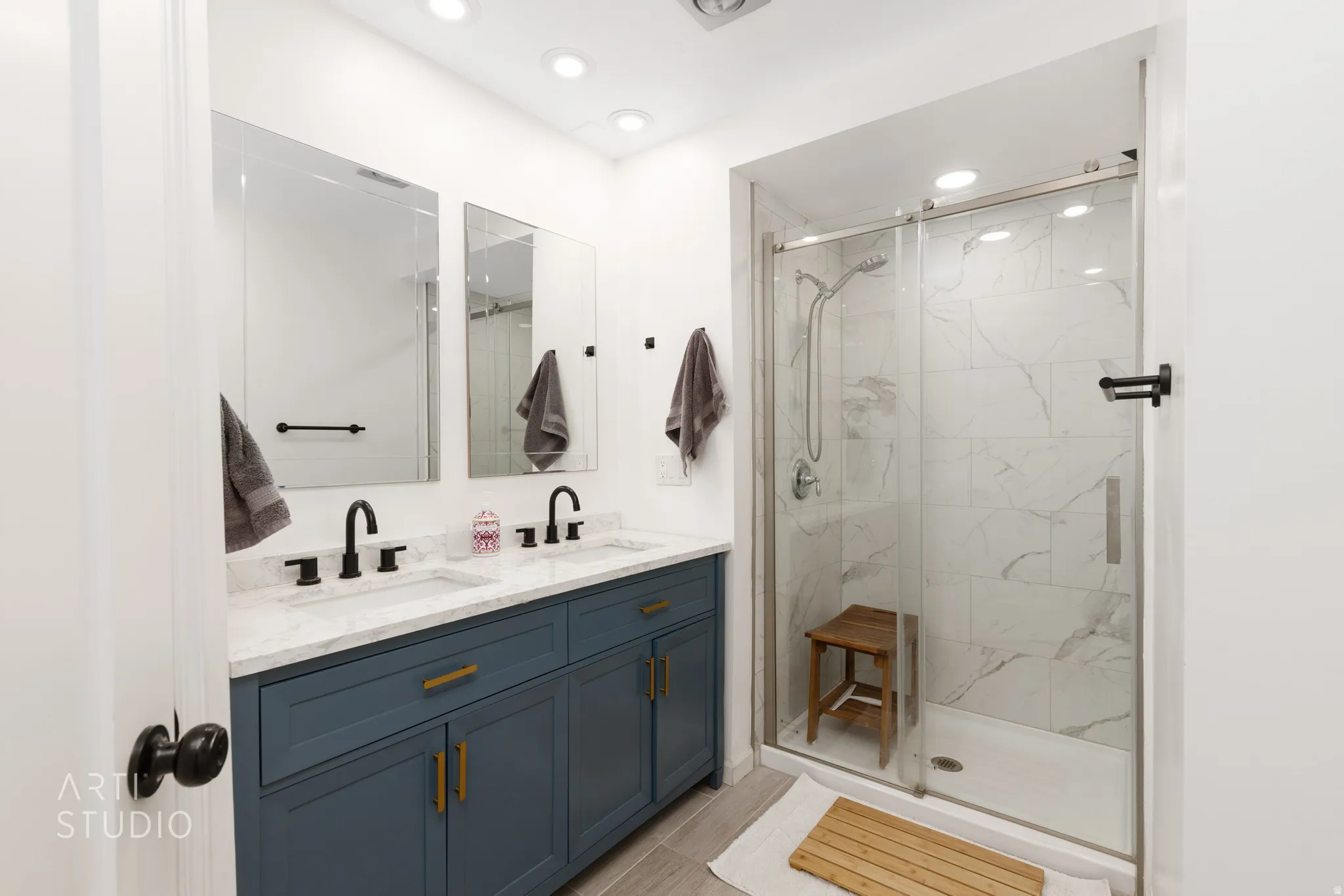 Dual vanity with dark blue cabinetry, matte black fixtures, and a light-colored countertop
