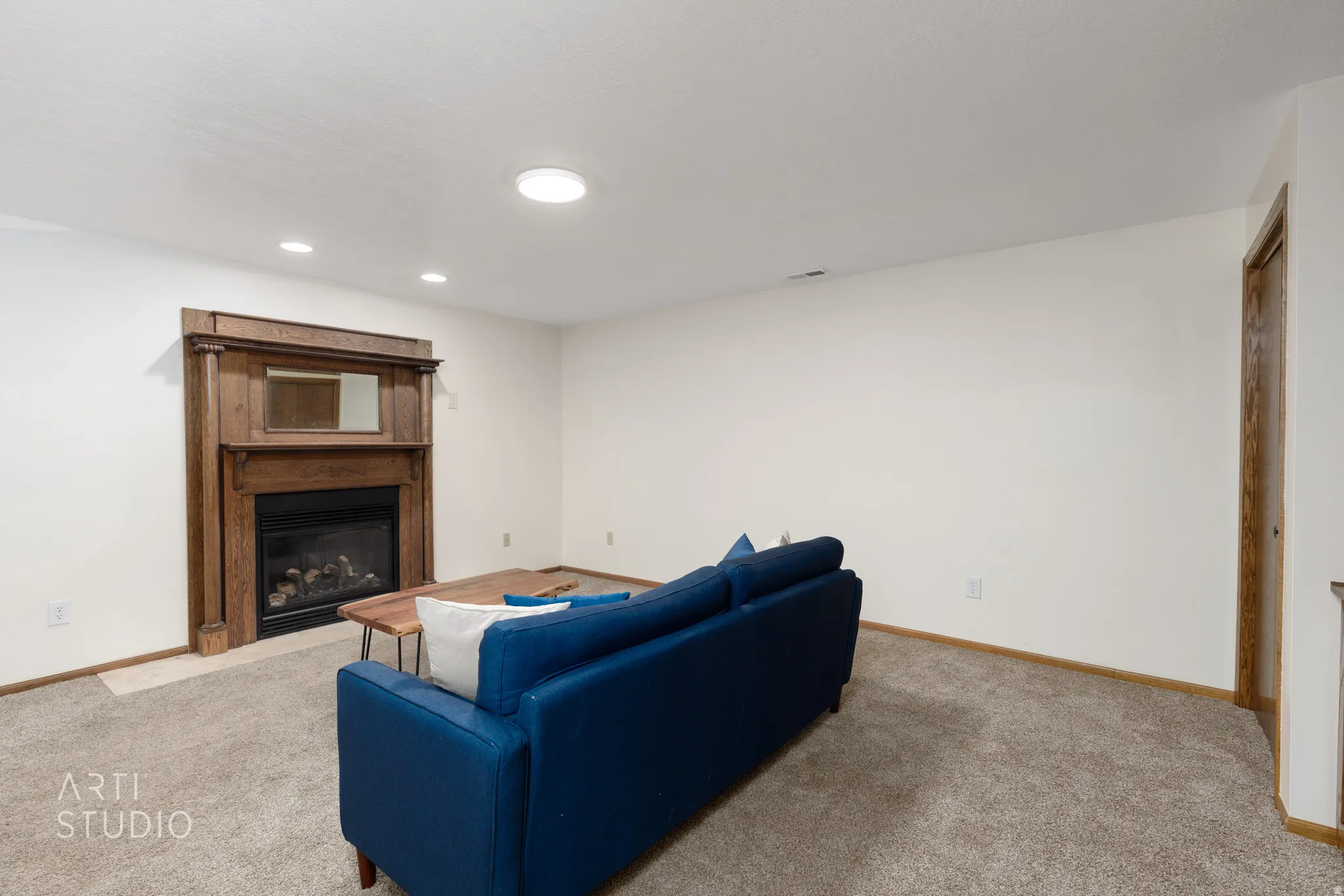 Built-in fireplace with a detailed wood mantel, recessed lighting, and a neutral carpeted floor
