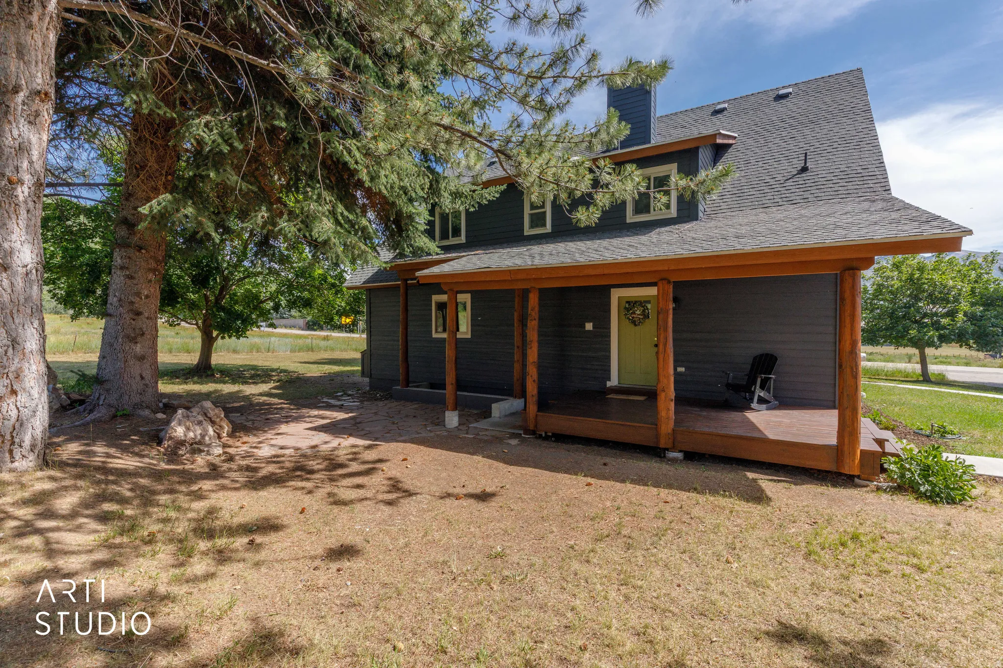 Property featuring dark gray siding, a covered porch with natural wood posts, a light green entry door, and a gray shingle roof