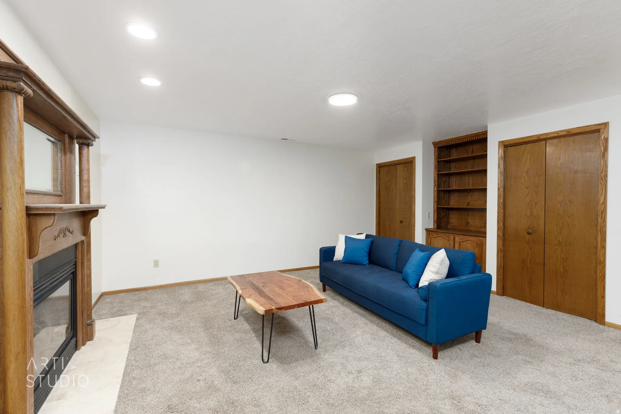 Built-in wooden fireplace mantel, recessed lighting, built-in wooden shelving, and two wooden paneled doors