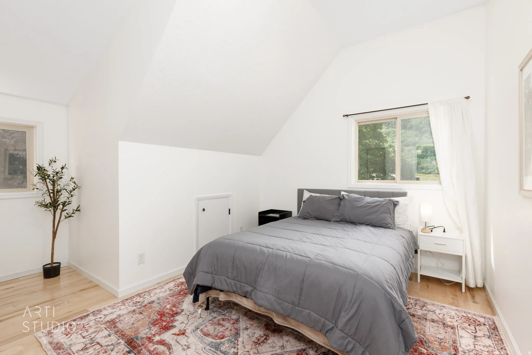 Slanted ceiling with recessed lighting, light wood-finish flooring, and white walls