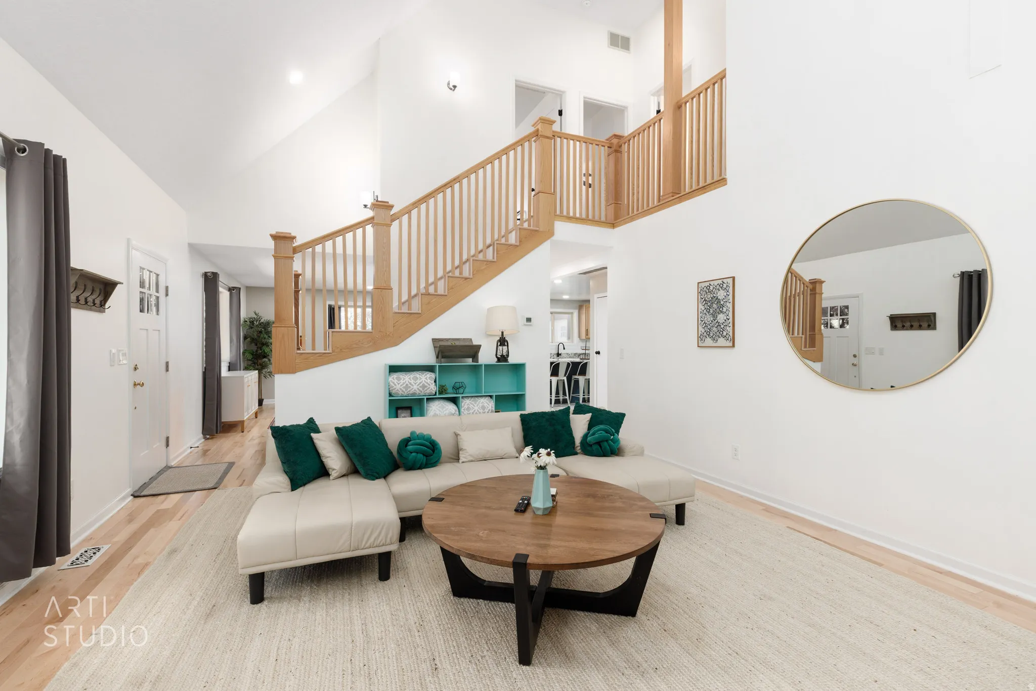 Vaulted ceilings with recessed lighting, light wood-finish flooring, natural wood staircase with balusters, and a split-pane entry door