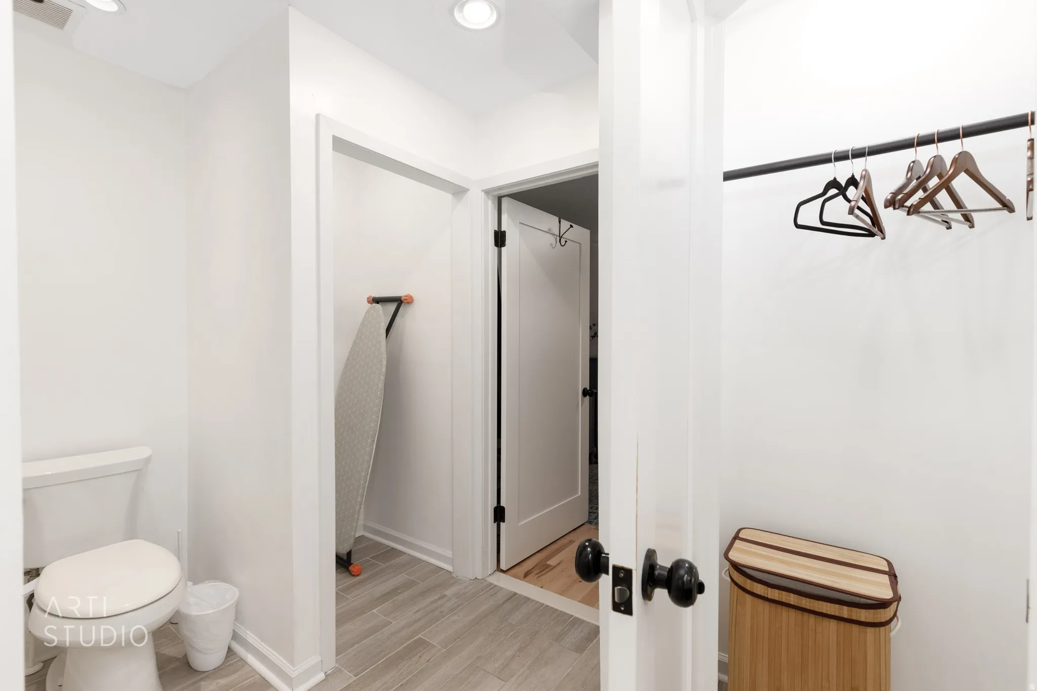 Recessed ceiling lighting, white walls, wood-finish flooring, and a built-in hanging rod