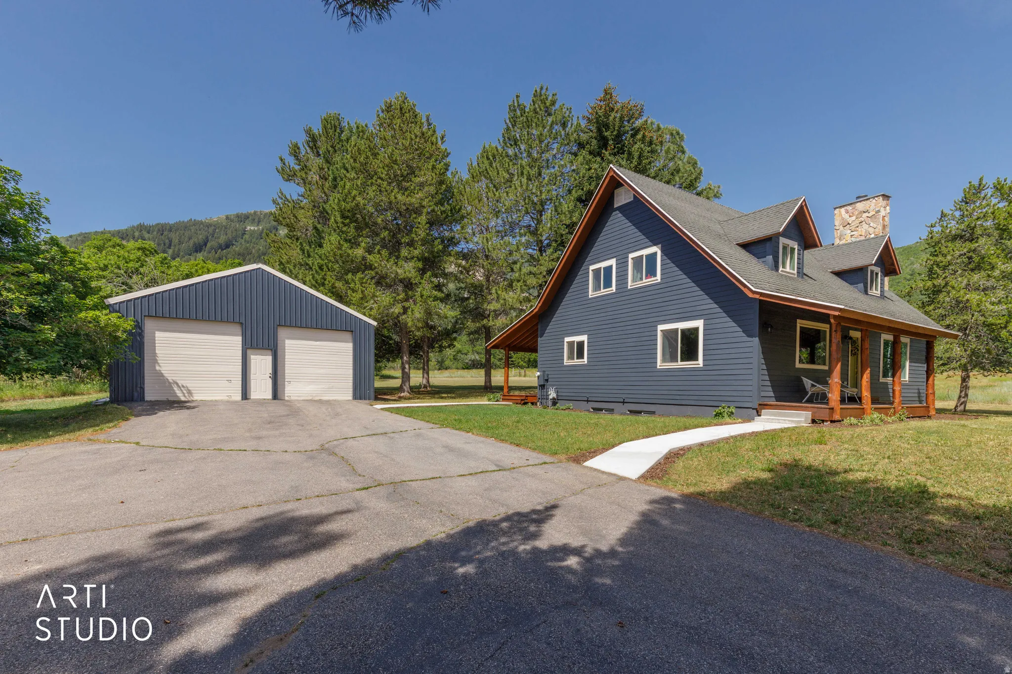Two-story residence featuring dormer windows, a stone-clad chimney, and a covered front porch with wood columns