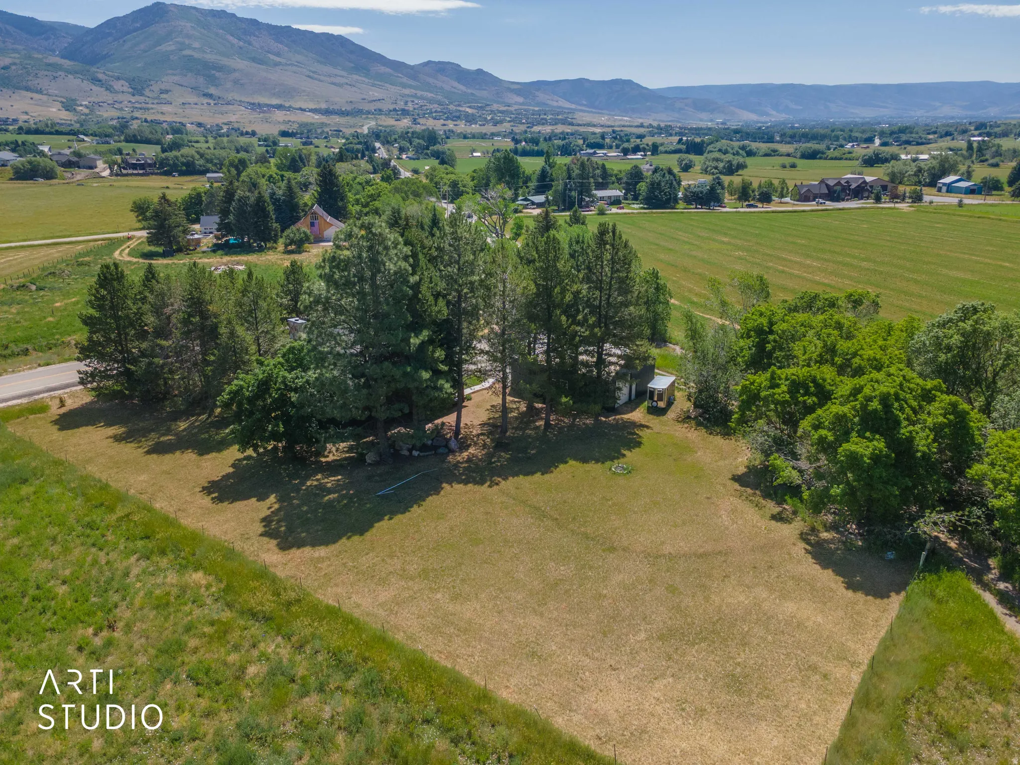 Expansive property with mature trees, green fields, and distant mountains